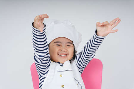 Pretty asian thai kid play role as a chef with cheerful expression isolate over white background.の写真素材
