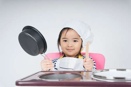 Pretty asian thai kid play role as a chef working at cooker station with boil pot.の写真素材