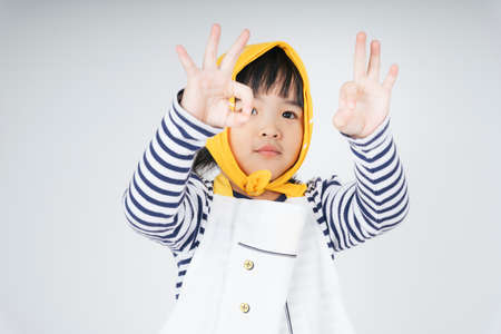 Pretty asian thai kid wearing yellow bandage showing ok gesture sign with both hands.