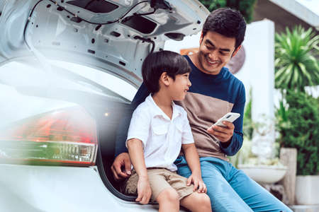 Asian thai father and son sitting at trunk car together.