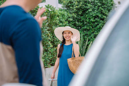 Beautiful asian tourist woman in blue dress wearing hat calling taxi with application on smartphone.の写真素材