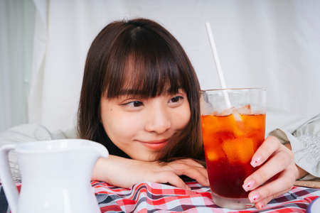 Close up portrait of asian woman holding ice thai tea cup.