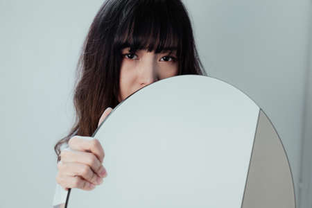 The eyes of curly long hair girl behind the oval mirror.の写真素材