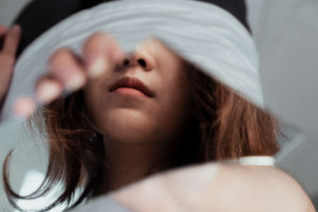 The reflection of a girl's mouth in a pieces of mirror in her hand.の写真素材
