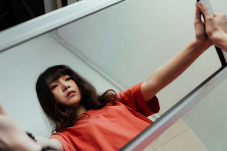 Curly long hair girl hold the mirror with her hands but her reflection shows her empty eyesight.