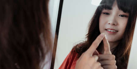 Curly long hair girl have fun with er reflection in the mirror while she point her index on it.の写真素材
