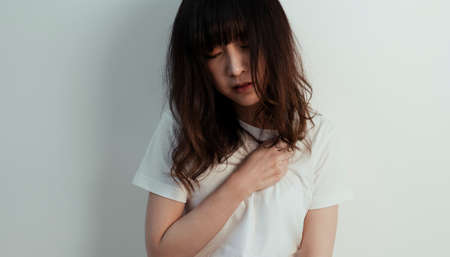 Curly long hair girl get heartache while she sit at the white wall.
