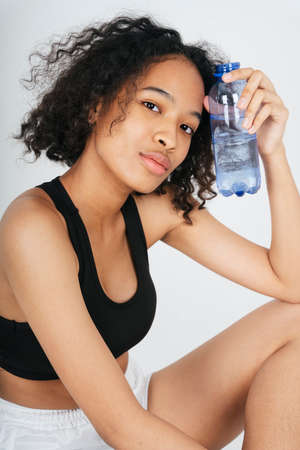 Portrait of mixed race african and thai woman holding a bottle of water.