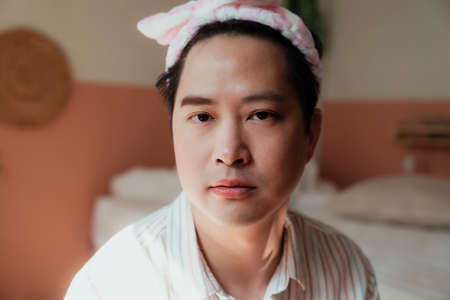 Portrait shot of asian gay with pink headband after makeup.