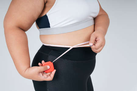 Healthy asian chubby woman in white sportbra and measuring tape. Lost weight concept.の写真素材