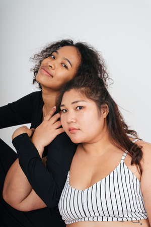 Chubby asian woman and african curly hairstyle woman over white background.の写真素材
