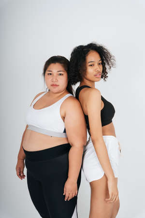 Portrait of diverse women with chubby asian and african woman in sportbra over white background.の写真素材