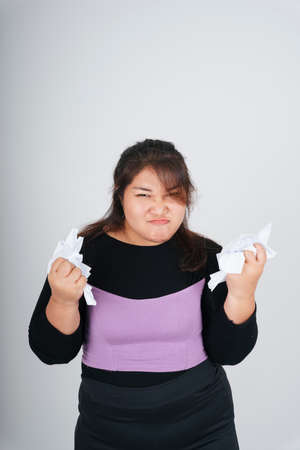 Angry asian chubby business woman torn up sheet paper with both hands.の写真素材