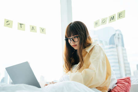 Young asian dark hair woman wearing eyeglasses using smartphone at home. Girl stay home due to...