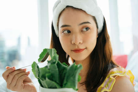 Young asian dark hair woman with white headband enjoy eating organic vegetable salad.の写真素材