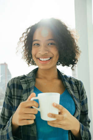Portrait of cheerful african curly hairstyle woman holding coffee cup.の写真素材