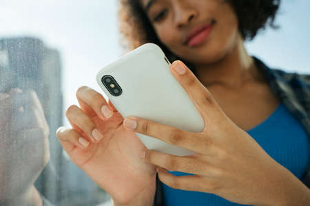African curly hairstyle woman enjoy using smartphone surfing internet.