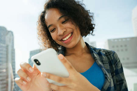 African curly hairstyle woman enjoy using smartphone surfing internet.の写真素材
