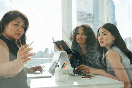 Three diverse asian and african business women working together in office.の写真素材