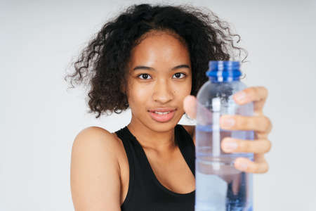 Close up portrait of african holding plastic water bottle on white background.