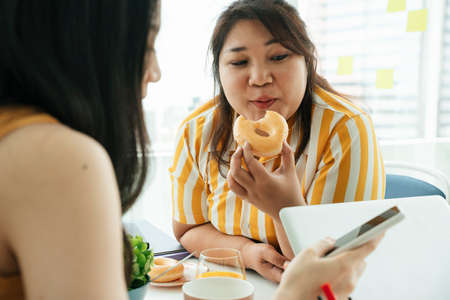 Fat business women eating unhealthy donut for lunch.の写真素材