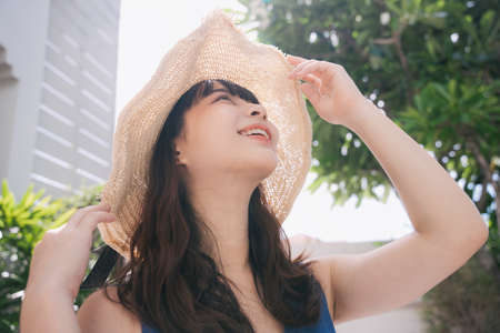 Portrait of young asian woman traveler wearing blue dress and hat outdoors in city.の写真素材