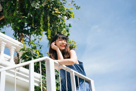 Young asian woman traveler wearing blue dress at balcony in sunny day.の写真素材