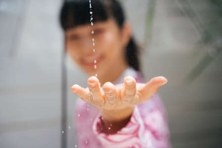 Young asian woman in pink shirt holding transparent umbrella touching raindrop in sunny day.
