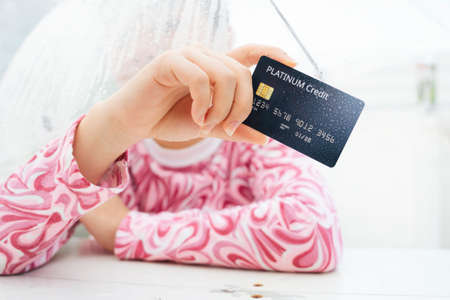 Hand of traveler woman in pink shirt holding credit card and umbrella. Shopping in rainy season...