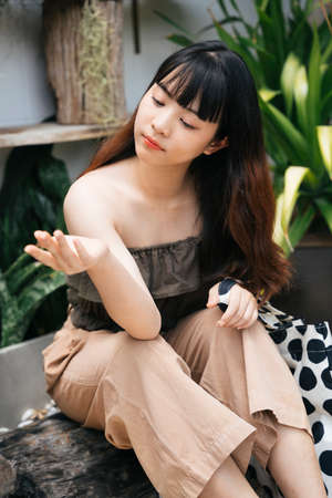 Young asian woman traveler sitting and touching the rain drop with hand at yard.の写真素材