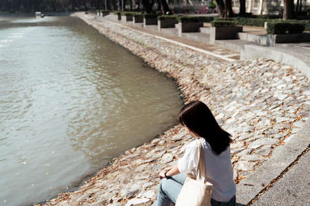 Cute girl in white t-shirt standing in sunlight at the pond in the yard.の写真素材