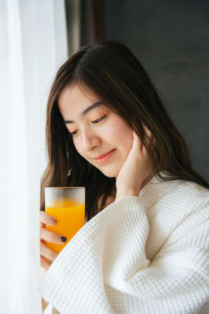 Beautiful asian woman drinking healthy fresh orange juice.の写真素材
