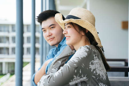 Asian couple traveler standing on hotel balcony looking at the view.の写真素材