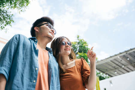 Asian couple traveler wearing sunglasses walking in city. Both looking up the sky.の写真素材