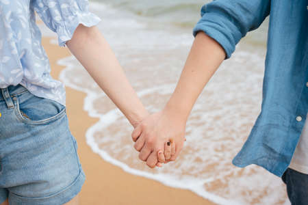 Close up - asian couple traveler holding hands on the beach.