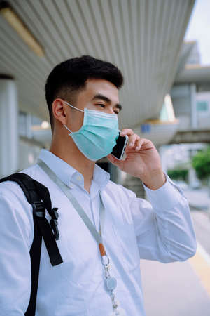 Business man wear mask using phone at bus stop in city.