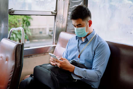 Asian business man using smartphone on a bus.の写真素材