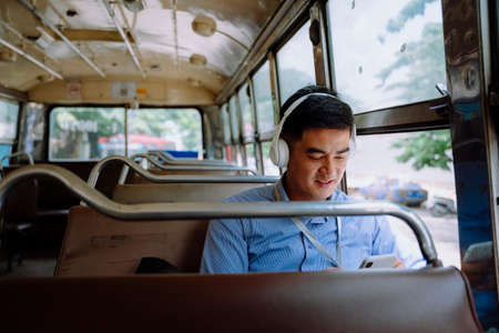 Asian business man listen to music with wireless headphone on a bus in Bangkok.の写真素材