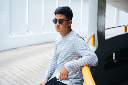 Fashion portrait - Asian man wear sunglasses outdoors in city.