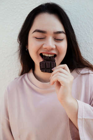 Long hair fat woman is loving every moment of eating chocolate.の写真素材
