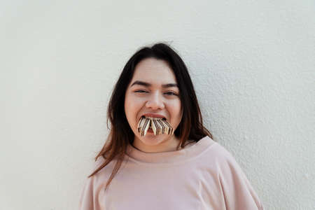 Fat woman in pink t-shirt bite five wafers in the same time.