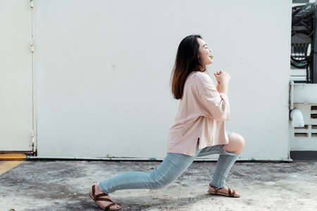 Long hair fat woman act like do yoga while bite the wafer in her mouth.