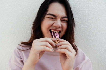 Snack lover woman eat lots of snack stick in the same time.の写真素材