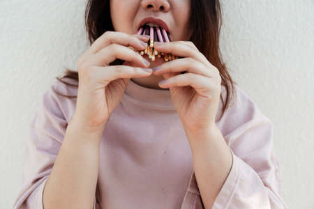 Cropped image of chocolate stick and strawberry stick are bitten by fat woman in pastel pink t-shirt.の写真素材