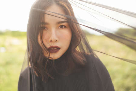 Black lady standing in the grassland wearing black vail, look at the camera with stunning eye sight.の写真素材