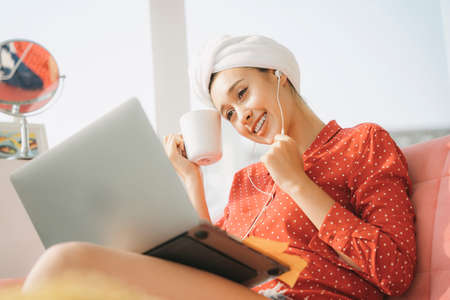 Work from home concept - Beautiful young woman in red pajamas shirt with towel bath head wrap...