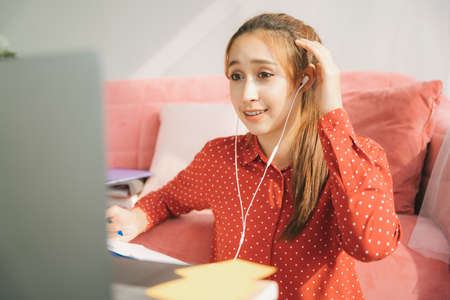 Work from home concept - Beautiful young woman in red pajamas shirt talking with colleagues from...