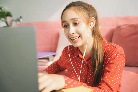 Work from home concept - Beautiful young woman in red pajamas shirt talking with colleague on...
