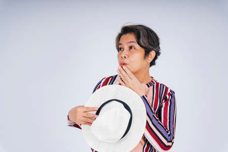 Portrait of excited and amazed old woman holding hat isolate over white background.の写真素材