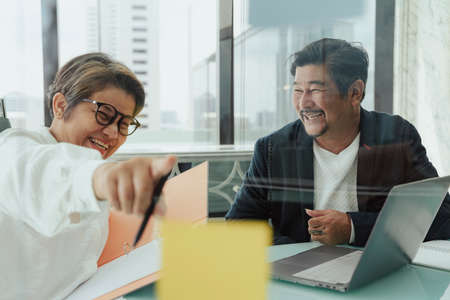 Old elderly senior business people working together in office, pointing at memo sticky note.の写真素材